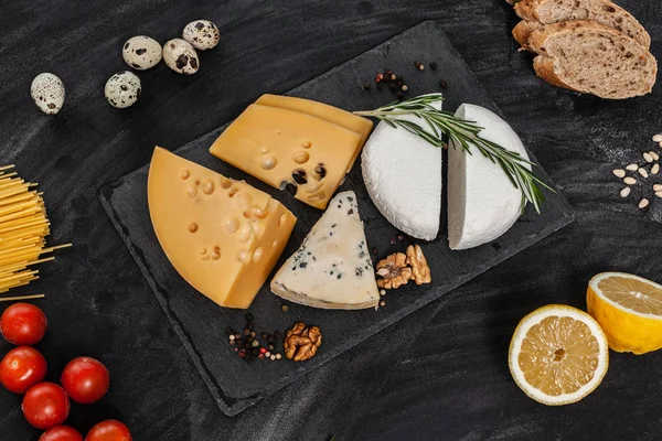 Siyah masanın üstünde farklı besin maddeleri olan peynir koleksiyonu.