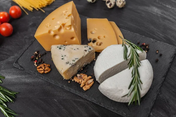 Siyah masanın üstünde farklı besin maddeleri olan peynir koleksiyonu.