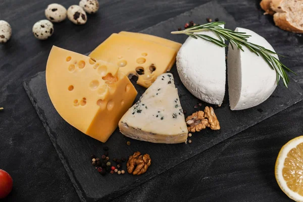 Siyah masanın üstünde farklı besin maddeleri olan peynir koleksiyonu.