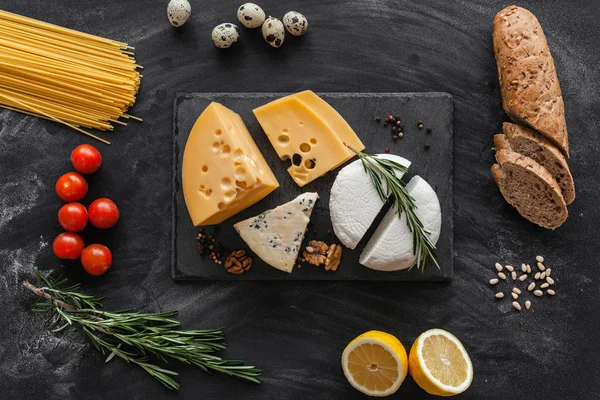 Siyah masanın üstünde farklı besin maddeleri olan peynir koleksiyonu.
