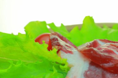 Ahşap bir gemide sebze ile Füme pastırma mı. Domates, salatalık, salata, dilimlenmiş jambon beyaz bir arka plan üzerinde ahşap bir gemide iştah açıcı