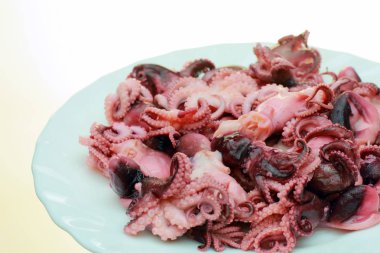 Bir plaka üzerinde Marine edilmiş ahtapot. Ahtapot beyaz bir arka plan üzerinde 3-5 cm uzunluğunda bir sürü