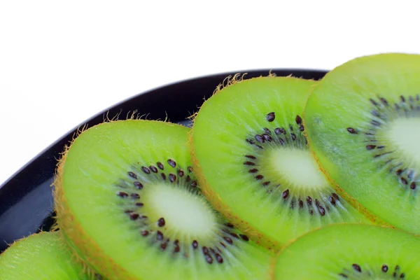 Întinde-te pe o farfurie de kiwi feliat. O mulțime de fructe verzi cu lumină strălucitoare în fundal ca fundal — Fotografie, imagine de stoc