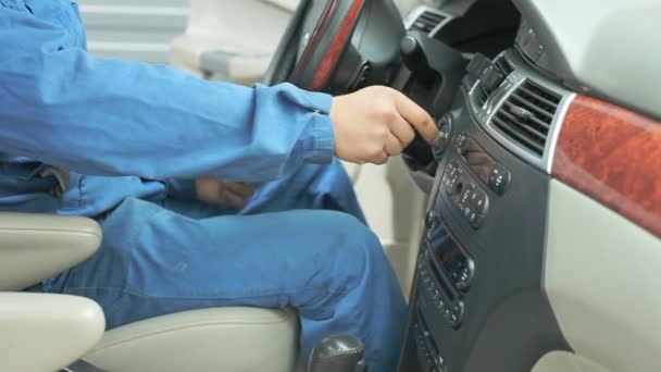 Un técnico vestido con un uniforme de trabajo está en el coche y comprueba la caja de cambios y el salpicadero — Vídeo de stock