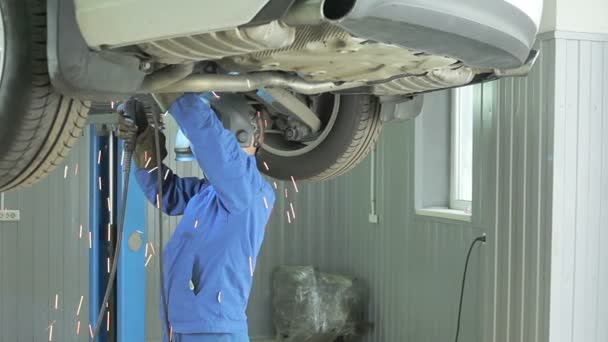 Mechanic skär av ljuddämpare i bilen. — Stockvideo