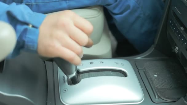 Een reparateur gekleed in een uniform van het werk is in de auto en controleert de versnellingsbak en dashboard — Stockvideo