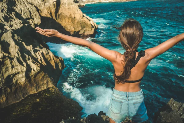 Dziewczyna z uniesionymi rękoma cieszyć się widokiem na ocean — Zdjęcie stockowe