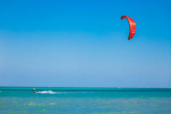 赤い海の上を滑空の赤い凧と Kitesurfer. — ストック写真