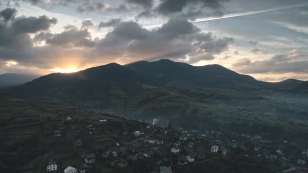 Pueblo de montaña contra el sol naciente desde detrás de las colinas — Vídeos de Stock