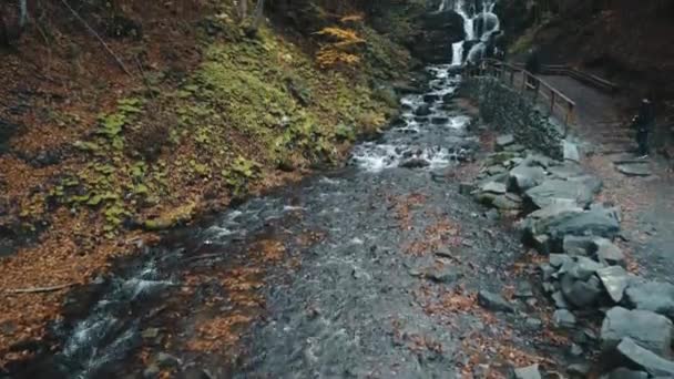 Schäumender Wasserfall fällt von felsigem Hügel und fließt auf Pfad — Stockvideo