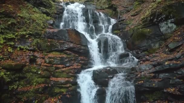 Гірський водоспад падає біля сірих великих скель з мохом — стокове відео