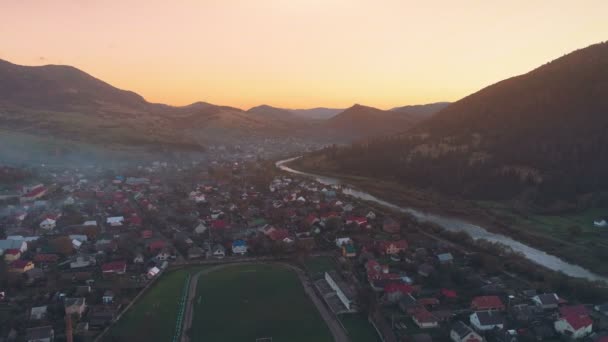 Pictorial town buildings against hills hiding setting sun — Stock Video