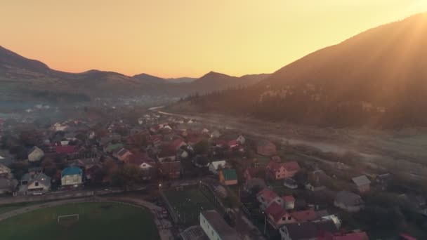 Bâtiments de la ville entourés de silhouettes de haute colline au coucher du soleil — Video