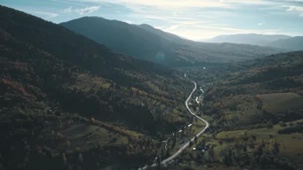 Road intertwines with thin mountain stream between hills — Stock Video