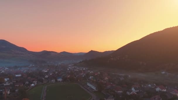 Malerisches Städtchen mit Fußballplatz am Flussufer auf Hügeln — Stockvideo