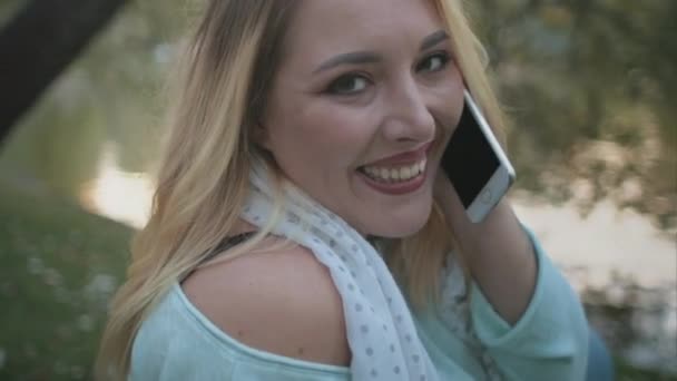 Blanke vrouw zitten op gras mobiele telefoon praten — Stockvideo