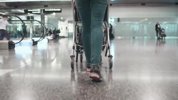 Frau mit Gepäckwagen läuft am Flughafen-Terminal — Stockvideo