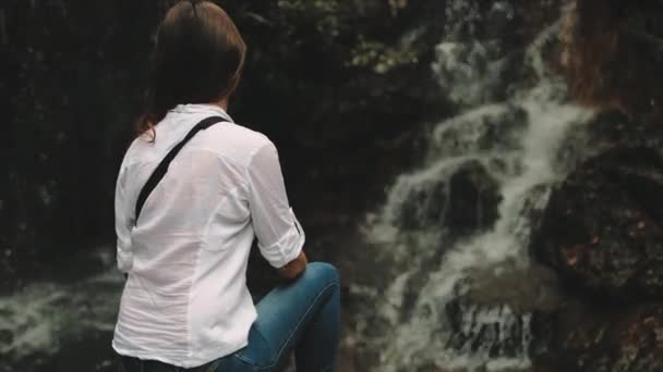 Kadın turist su sıçratan tropikal şelaleye bakar — Stok video