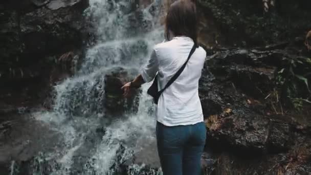 Woman reaching out hands to splashing waterfall — Stock Video