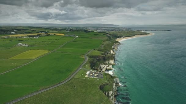 Paisagem rural irlandesa costa precipício tiro panorâmico aéreo: campos verdes, prados e baía do oceano, céu nublado — Vídeo de Stock