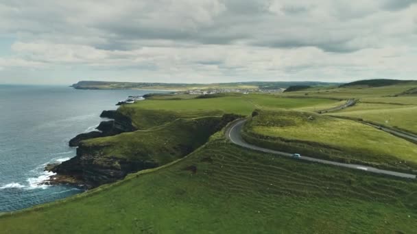 Irelands λιβάδια εναέρια άποψη: οδικά αυτοκίνητα οδήγηση στο παρασκήνιο των πράσινων πεδίων. Ιρλανδικές γεωργικές εκτάσεις — Αρχείο Βίντεο