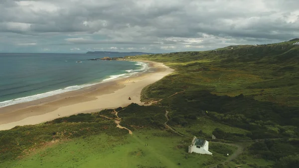 Ocean Bay homokos strand légi panoráma alatt szürke vastag felhők. Zöld rétek az ír völgyekben — Stock Fotó