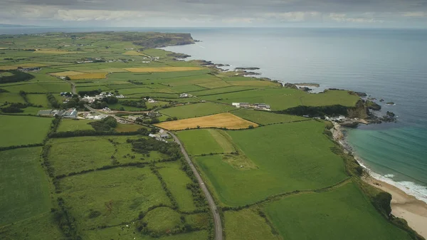 Paisagem irlandesa campos verdes aéreos tiro: estrada ao longo dos prados. Irlanda plantas e explorações agrícolas — Fotografia de Stock