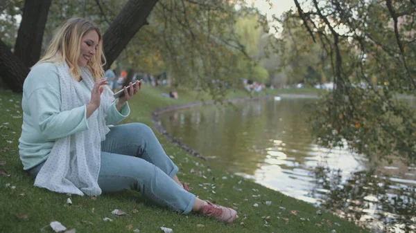 Mujer más tamaño hablar Smartphone sentarse en la orilla del río — Foto de Stock