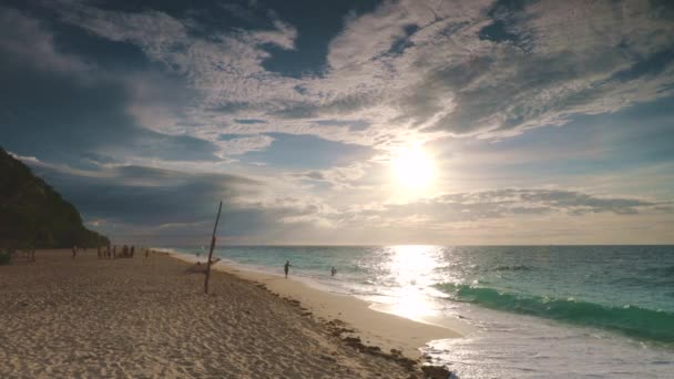 Wschód słońca Filipiny ocean plaża: ludzie odpoczywają na piasku, woda w zatoce wybrzeża morskiego, wschód słońca na błękitnym niebie — Wideo stockowe