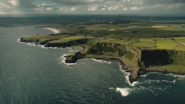 Aerial Ireland green farmlands: ocean gulf with stony shore (en inglés). Increíbles granjas y cabañas irlandesas — Vídeos de Stock