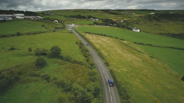 アイルランドの農村部の道路の空撮:車の交差点付近に乗る。丘の上のコテージ、牧草地、フィールド — ストック動画