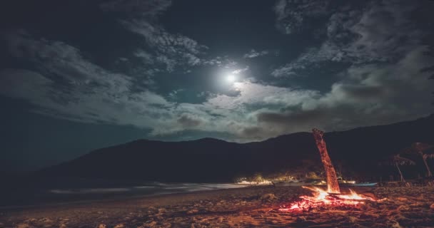 Tajlandia plaża noc timelapse: ogień na piasku ocean brzeg z sylwetką górską na księżycu, gwiazdy niebo — Wideo stockowe