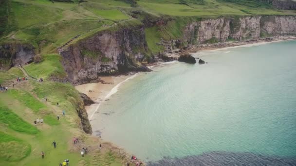 Irlanda oceano costiera isola vista aerea: persone trekking ponte corda Carrick-a-Rede a scogliera verde — Video Stock