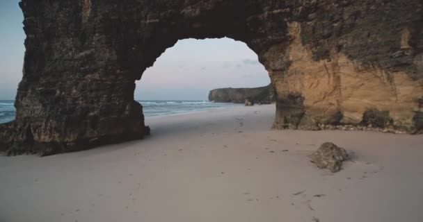 Buraco gigante de parede de rocha na praia de areia, baía do oceano em vista aérea. Formação geológica rochosa única — Vídeo de Stock