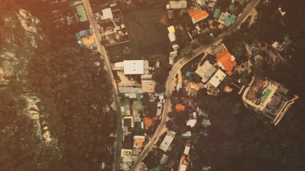 Paisaje urbano aéreo de arriba hacia abajo con albergues, casas, edificios techos y carreteras en el bosque tropical verde — Vídeos de Stock