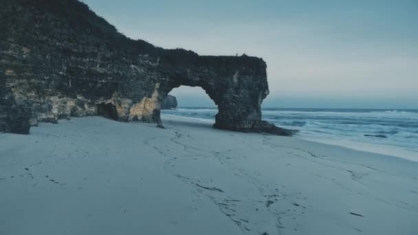 Kalter hellblauer Strand an einer Meeresbucht mit Wellen aus der Luft. Naturdenkmal am Meer mit Felswand — Stockvideo