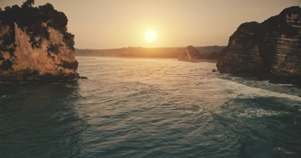 Pôr do sol em câmera lenta na costa do oceano de rocha com ondas na vista aérea da superfície da água. Ninguém paisagem natureza — Vídeo de Stock