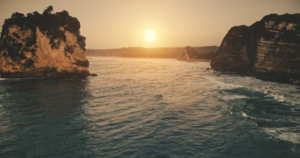 Ηλιοβασίλεμα στη βραχώδη ακτή του ωκεανού με κύματα στην επιφάνεια του νερού σε εναέρια θέα. Επική κανείς φύση στον ήλιο που δύει — Φωτογραφία Αρχείου