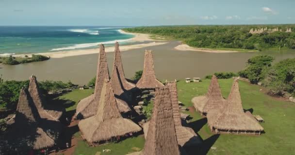 砂の海の海岸の航空で伝統的な村のスローモーション。インドネシアの集落、わら屋根の家 — ストック動画