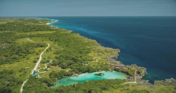 Uitzicht vanuit de lucht op het turquoise zoutwatermeer bij groene tropische bomen. Gebouwen, weg bij groene vallei — Stockfoto