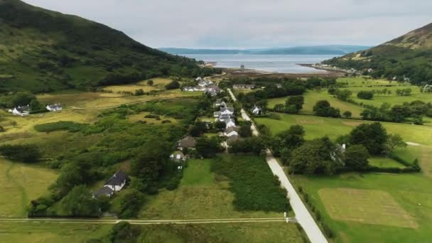 Village écossais vue aérienne : route en été nuageux. Chalets, distillerie, camping dans la vallée — Video