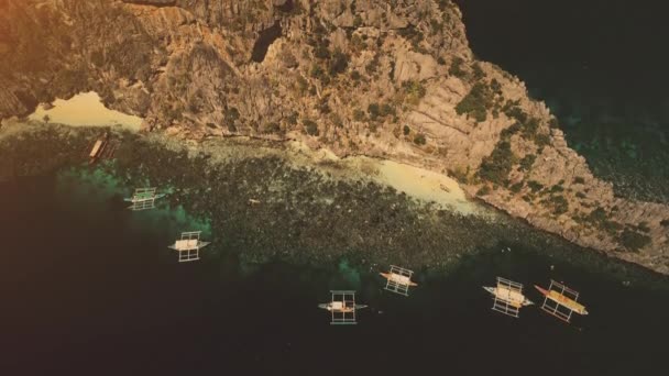 Traditionelle philippinische Boote bei Sonnenuntergang leichte Luftaufnahme. Wassertransport in der Meeresbucht, Sandstrand — Stockvideo