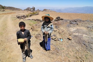 Hajjarah, Yemen - Mart 14, 2010: Tanımlanamayan çocuk - kız ve erkek kardeşim okaliptüs toprak yol üzerinde boncuk köyü satmak. Eğitim için küçük bir fırsat ile en fakir ülkede çocuklar büyümek