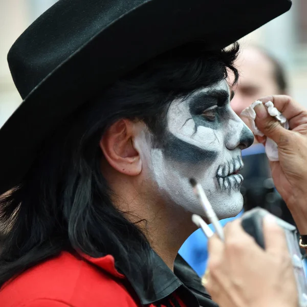 Moscow, Rusya Federasyonu - 29 Haziran 2018: Kız katılımcı şeker kafatası makyaj yüzündeki Dia de los Muertos Meksika Karnaval sırasında bir adam yapar. Ölülerin günü