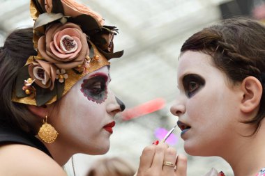 Moscow, Rusya Federasyonu - 29 Haziran 2018: Kız katılımcı Dia de los Muertos Meksika Karnaval sırasında diğer kız yüz şeker kafatası makyaj yapar. Ölülerin günü