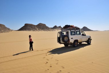Sahara, Mısır - 26 Aralık 2008: Ain Abu havas çölde off-road araç yakınındaki gösterilen turist kadın. Aşırı çöl safari Mısır'daki yerel turistik cazibe biridir