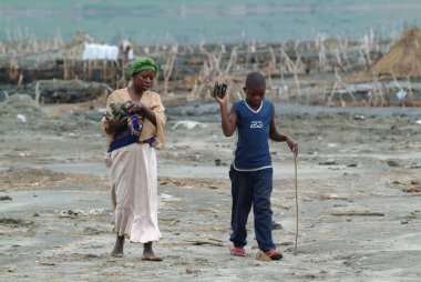 Katwe, Uganda - 29 Ağustos 2010: Anne ve oğlu tuz parçaları taşıyor. Katwe tuz gölü, uzun yıllar önce volkanik patlamayla oluşan tuz madenciliğinin yapıldığı geleneksel bir göldür.