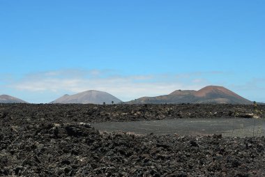 Lanzarote 'nin uçsuz bucaksız boşluğu ve yalnızlığı kara donmuş lav volkanik çölü ve arka planda volkanlar. Lanzarote, Kanarya Adası. İspanya