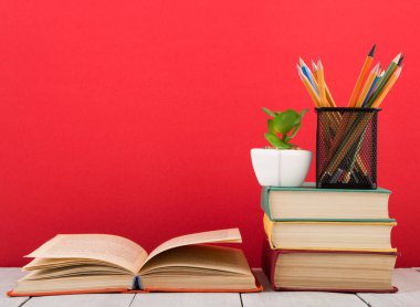 Eğitim ve bilgelik kavramı - ahşap masa üzerinde açık kitap, kırmızı arkaplan