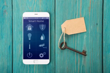 Ahşap masada akıllı ev uygulaması olan akıllı telefon.